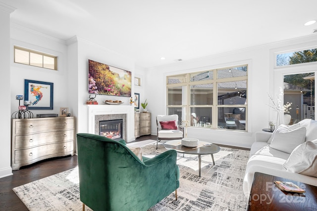 living room with ornamental molding, a tiled fireplace, and hardwood / wood-style floors