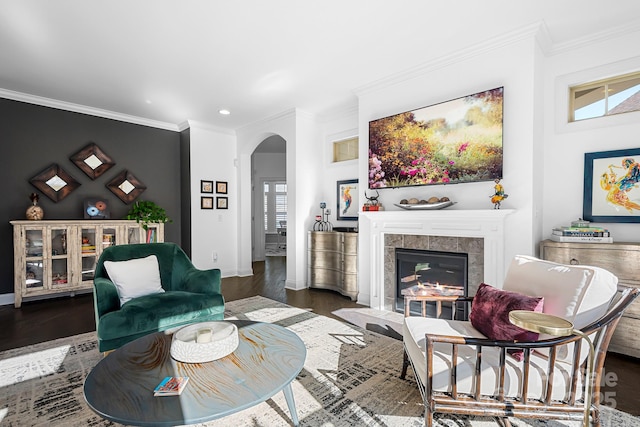 living room featuring dark hardwood / wood-style flooring, a tiled fireplace, crown molding, and a healthy amount of sunlight