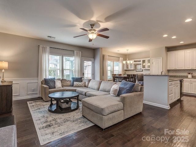 living room featuring dark wood-type flooring and ceiling fan with notable chandelier