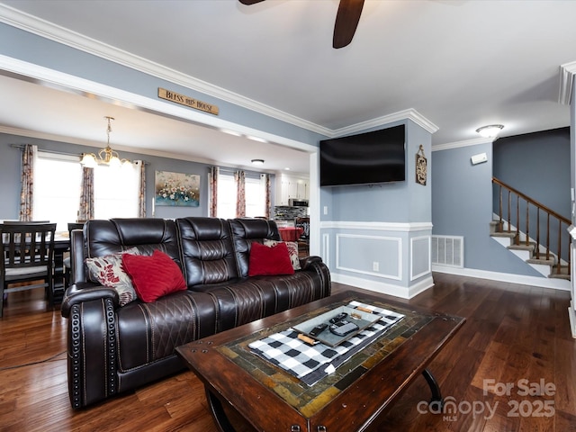 living room featuring dark hardwood / wood-style flooring, ceiling fan with notable chandelier, and ornamental molding