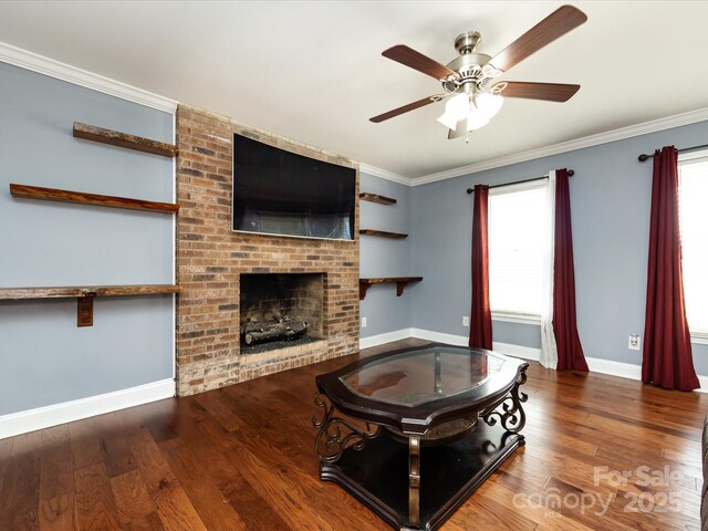 living room featuring a brick fireplace, crown molding, wood-type flooring, and ceiling fan