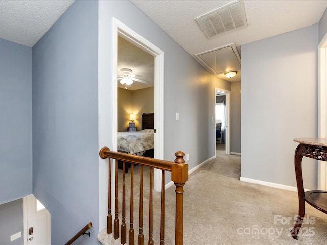 hall featuring light colored carpet and a textured ceiling