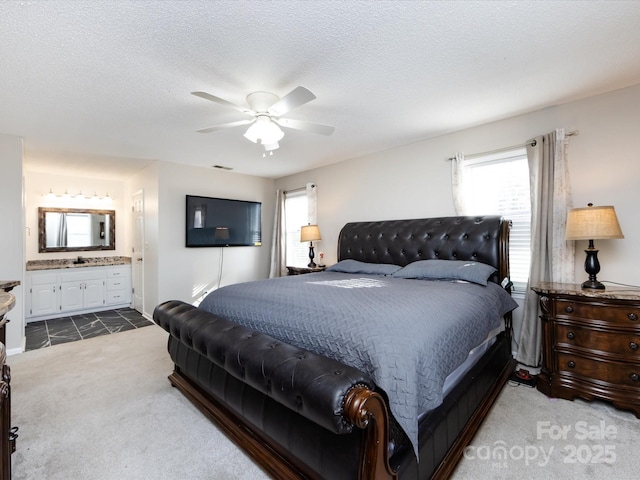 carpeted bedroom featuring multiple windows, connected bathroom, a textured ceiling, and ceiling fan