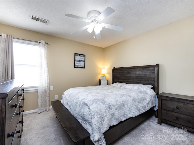 bedroom with ceiling fan, light carpet, and a textured ceiling