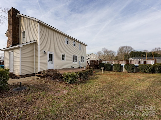 rear view of house with a wooden deck, a yard, and a patio