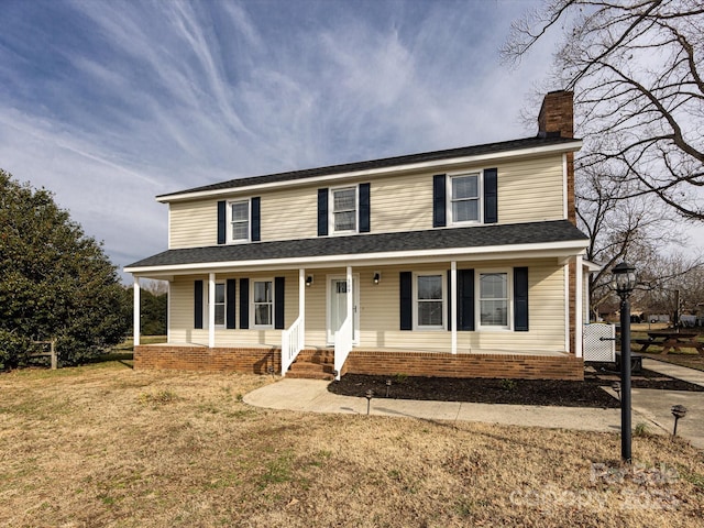 view of front facade featuring a front yard, covered porch, and a chimney