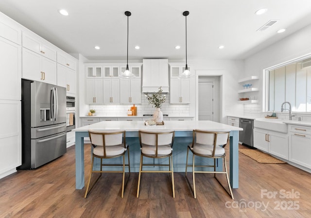 kitchen with a kitchen island, dark hardwood / wood-style floors, white cabinetry, hanging light fixtures, and stainless steel appliances