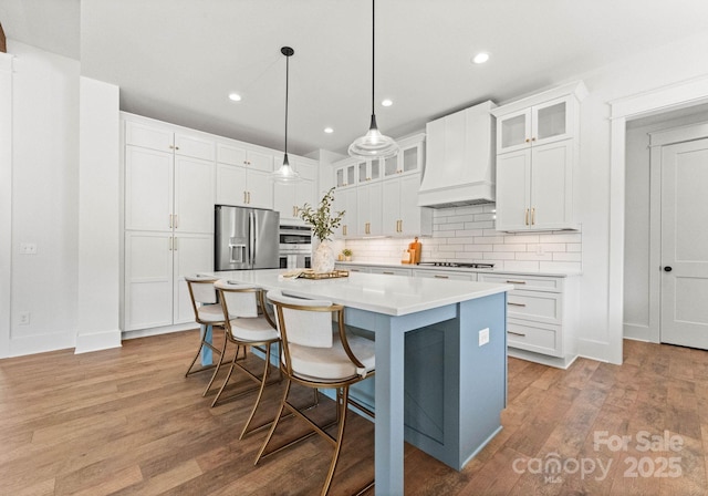 kitchen with white cabinetry, custom exhaust hood, stainless steel appliances, and a center island