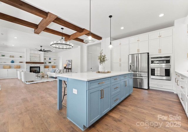 kitchen with white cabinetry, beam ceiling, pendant lighting, and appliances with stainless steel finishes