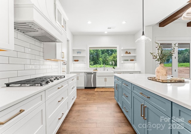 kitchen with hanging light fixtures, white cabinetry, appliances with stainless steel finishes, and custom range hood