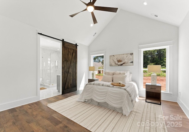 bedroom with ensuite bathroom, high vaulted ceiling, ceiling fan, a barn door, and hardwood / wood-style floors