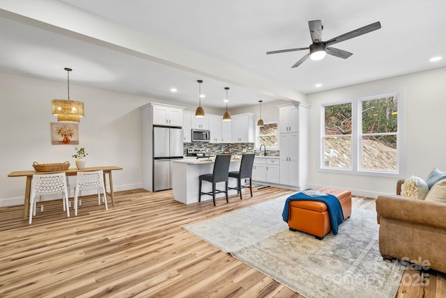 living room featuring ceiling fan, sink, and light hardwood / wood-style flooring