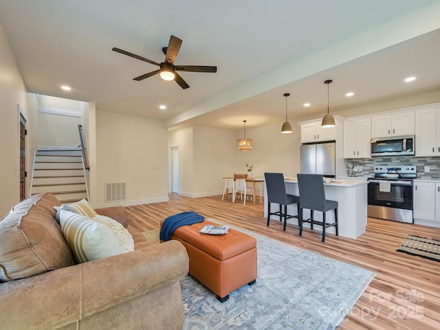 living room with ceiling fan and light hardwood / wood-style floors