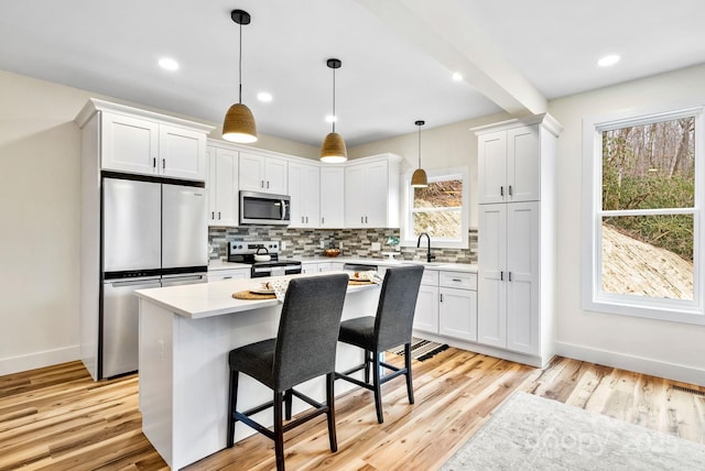 kitchen with pendant lighting, a center island, white cabinets, and appliances with stainless steel finishes