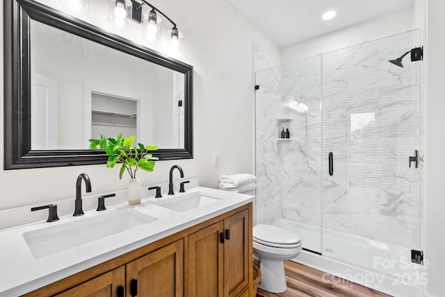 bathroom featuring wood-type flooring, a shower with door, and vanity