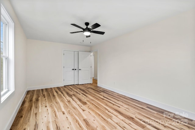 unfurnished bedroom featuring light wood-type flooring, ceiling fan, and a closet