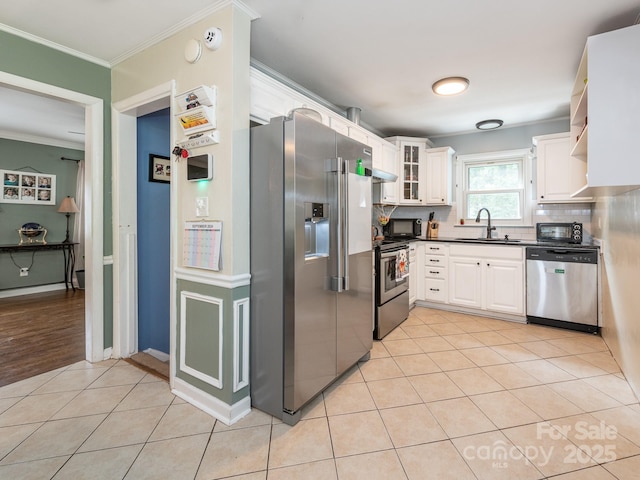 kitchen with white cabinetry, sink, ornamental molding, light tile patterned floors, and stainless steel appliances