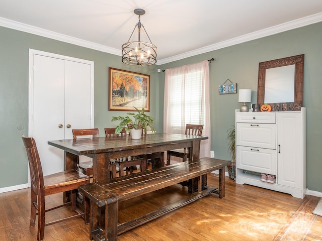 dining area with hardwood / wood-style flooring, ornamental molding, and a chandelier