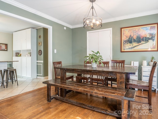 dining room featuring ornamental molding, an inviting chandelier, and light hardwood / wood-style flooring