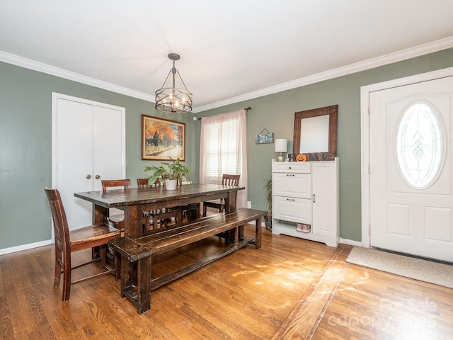 dining area with crown molding, an inviting chandelier, and hardwood / wood-style floors