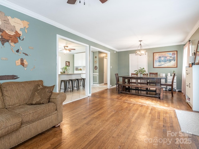 living room with ornamental molding, ceiling fan with notable chandelier, and hardwood / wood-style floors