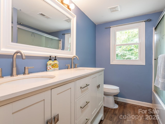 full bathroom with toilet, wood-type flooring, bath / shower combo with glass door, and vanity