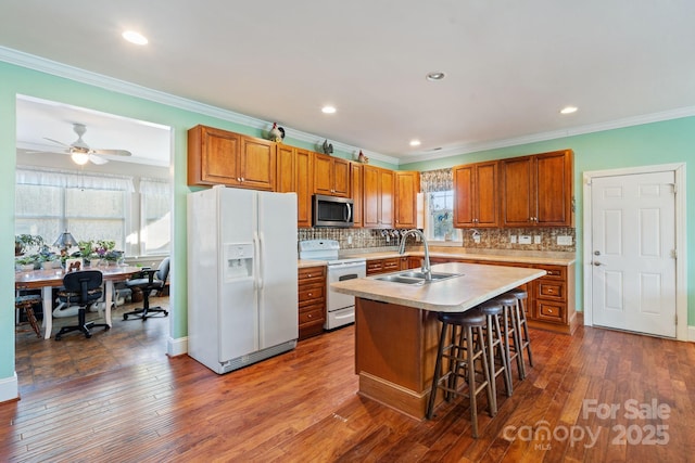 kitchen with white appliances, a healthy amount of sunlight, a kitchen island with sink, and sink