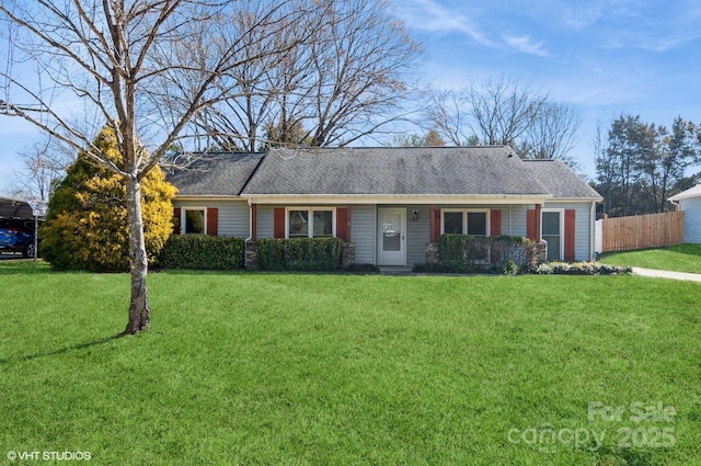 ranch-style house with a shingled roof, fence, and a front lawn