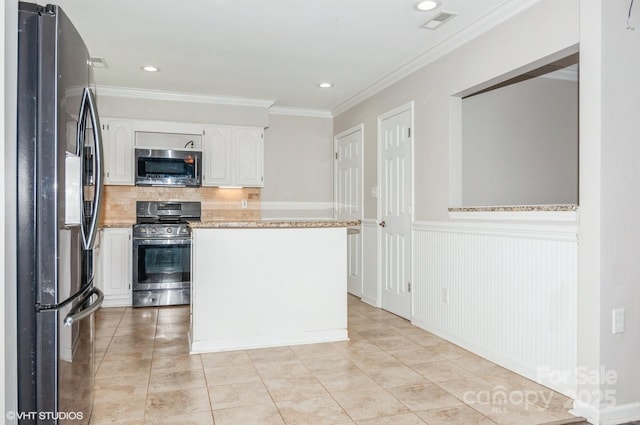 kitchen featuring decorative backsplash, white cabinets, light stone counters, appliances with stainless steel finishes, and crown molding