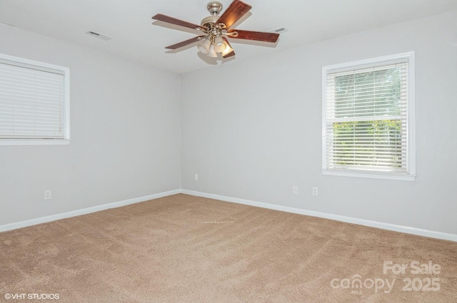 carpeted empty room featuring ceiling fan, visible vents, and baseboards