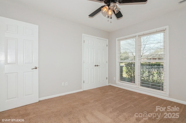 unfurnished bedroom featuring a closet, carpet flooring, a ceiling fan, and baseboards