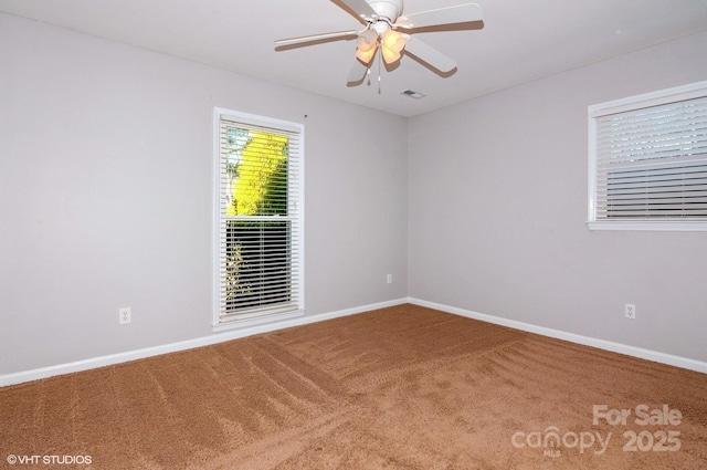 carpeted spare room with a ceiling fan, visible vents, and baseboards