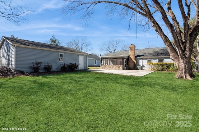 rear view of house featuring a chimney, a lawn, and a patio