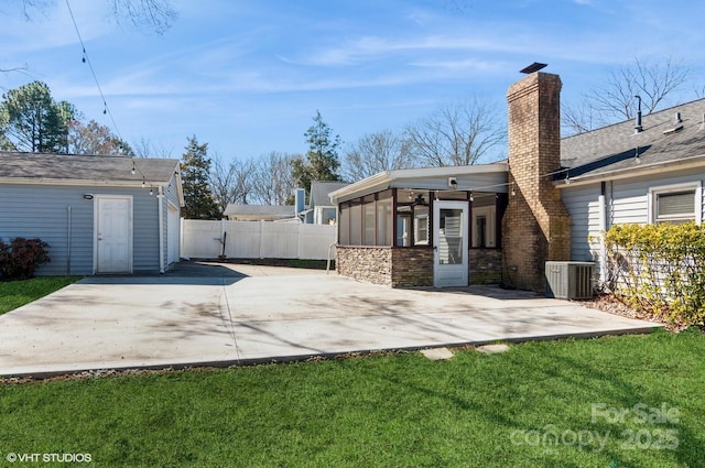 back of property featuring a yard, a chimney, a patio area, fence, and cooling unit