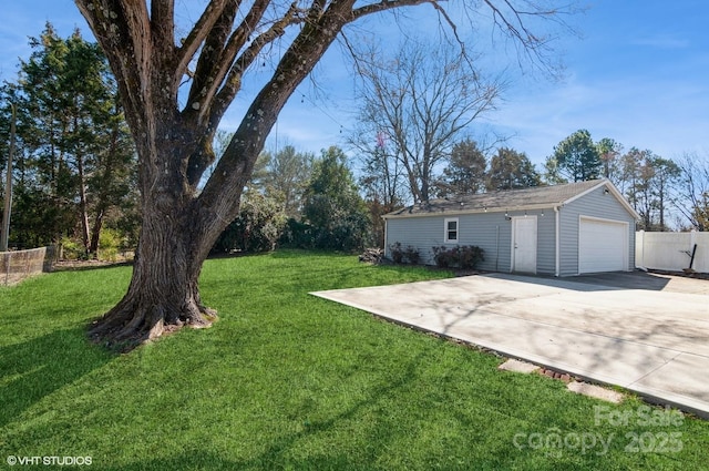 view of yard featuring driveway, a detached garage, and an outbuilding