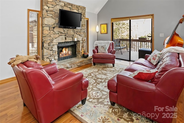 living room featuring a fireplace, vaulted ceiling, and light wood-type flooring