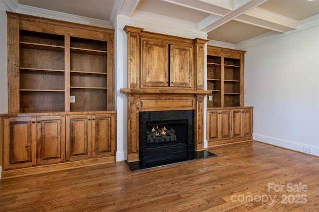 unfurnished living room featuring a fireplace, wood-type flooring, ornamental molding, and beamed ceiling