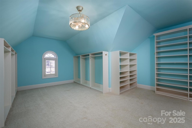 spacious closet with vaulted ceiling, light carpet, and a notable chandelier