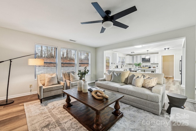 living room with ceiling fan and light wood-type flooring