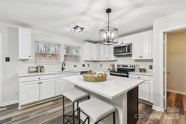 kitchen with sink, white cabinetry, appliances with stainless steel finishes, a kitchen island, and pendant lighting