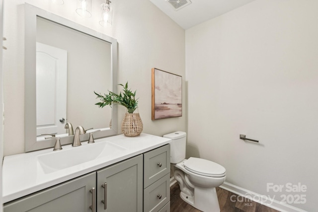 bathroom with hardwood / wood-style flooring, vanity, and toilet