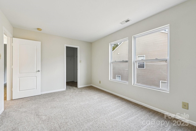 unfurnished bedroom featuring a spacious closet, light carpet, and a closet