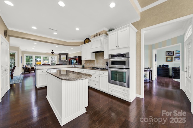 kitchen featuring dark wood-type flooring, white cabinetry, double oven, backsplash, and kitchen peninsula