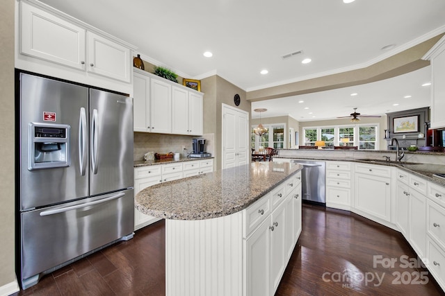 kitchen with a kitchen island, appliances with stainless steel finishes, sink, white cabinets, and kitchen peninsula