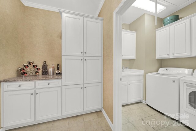 washroom featuring sink, light tile patterned floors, crown molding, independent washer and dryer, and cabinets