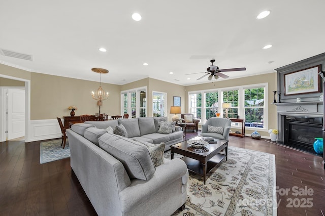 living room featuring ornamental molding, dark hardwood / wood-style flooring, and ceiling fan with notable chandelier