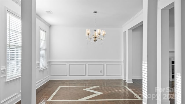 unfurnished dining area with a notable chandelier, crown molding, and dark parquet floors