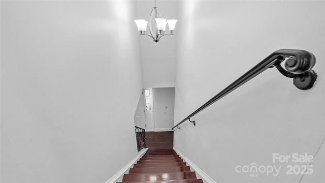 staircase with wood-type flooring and a notable chandelier