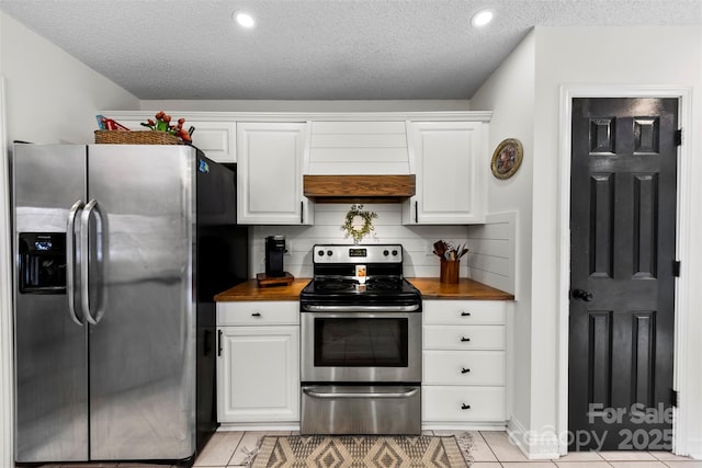 kitchen featuring butcher block countertops, appliances with stainless steel finishes, white cabinetry, tasteful backsplash, and a textured ceiling