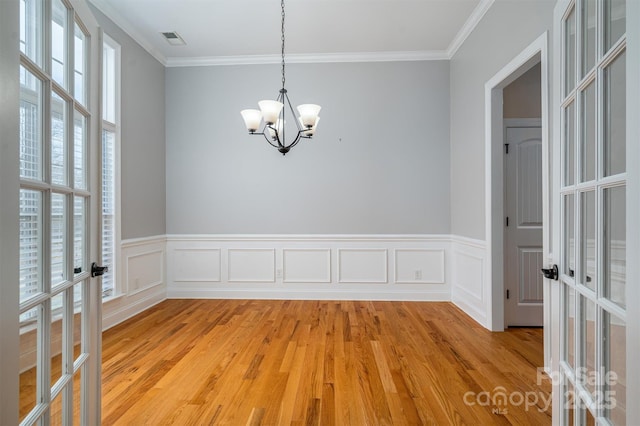 unfurnished room with french doors, crown molding, a chandelier, and light hardwood / wood-style floors